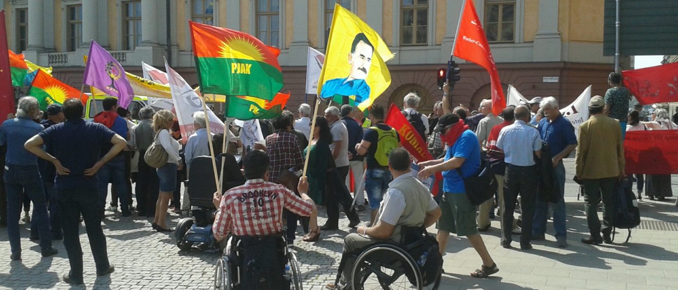 Un manifestant tient d'une main le drapeau du PJAK (organisation du Kurdistan iranien) et de l'autre un portrait d'Abdullah Öcalan, lors d'une manifestation pour la reconnaissance du peuple kurde à Stockholm, le 1er juin 2016. ©AD