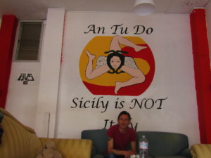 Giorgio Martinico devant le tag "Sicily is not Italy" du centre social autogéré Anomalia Crédits : Elsa Pécot